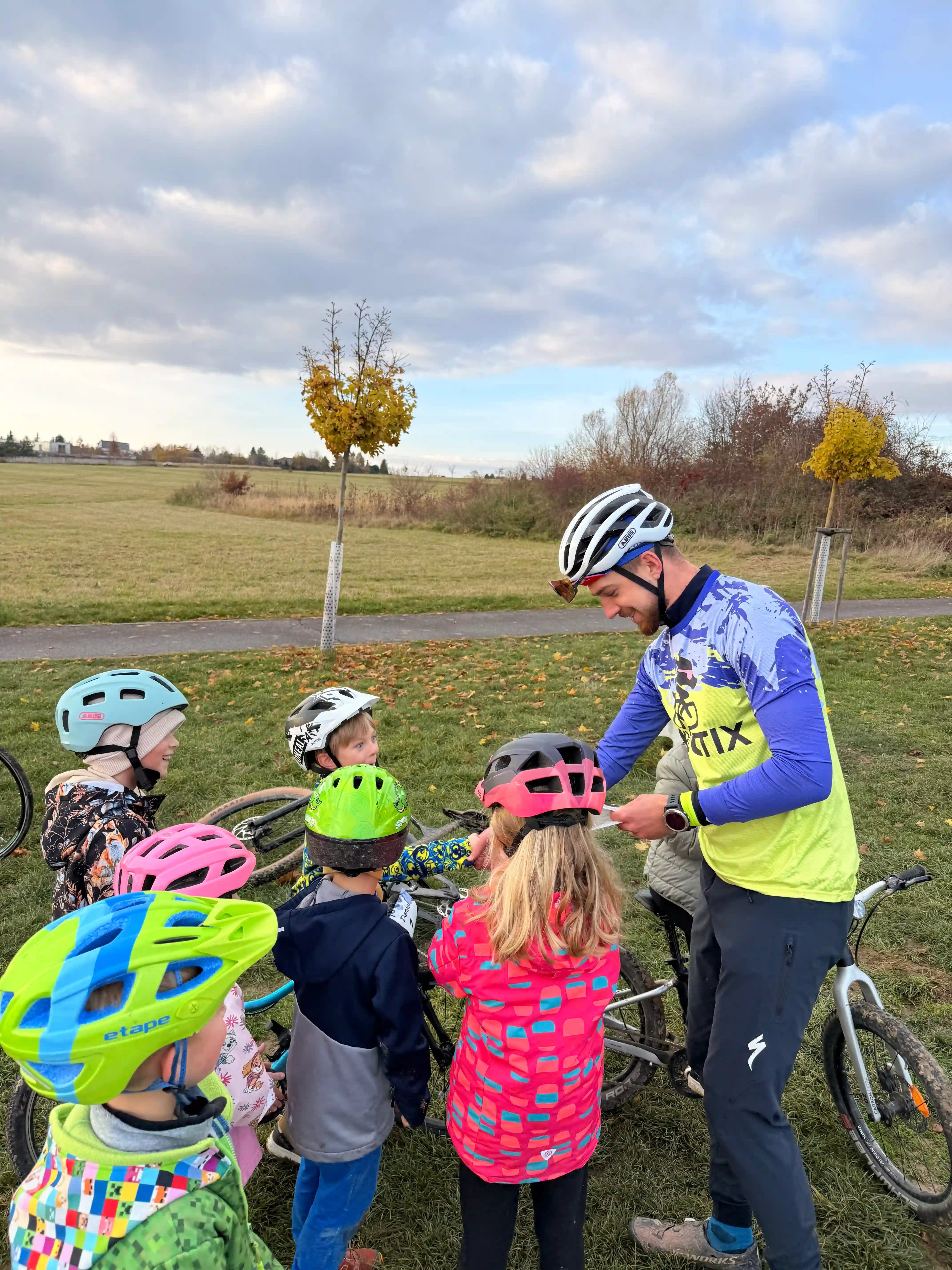 Trenér rozdává vysvědčení dětem za úspěšné zvládnutí cyklokroužku.