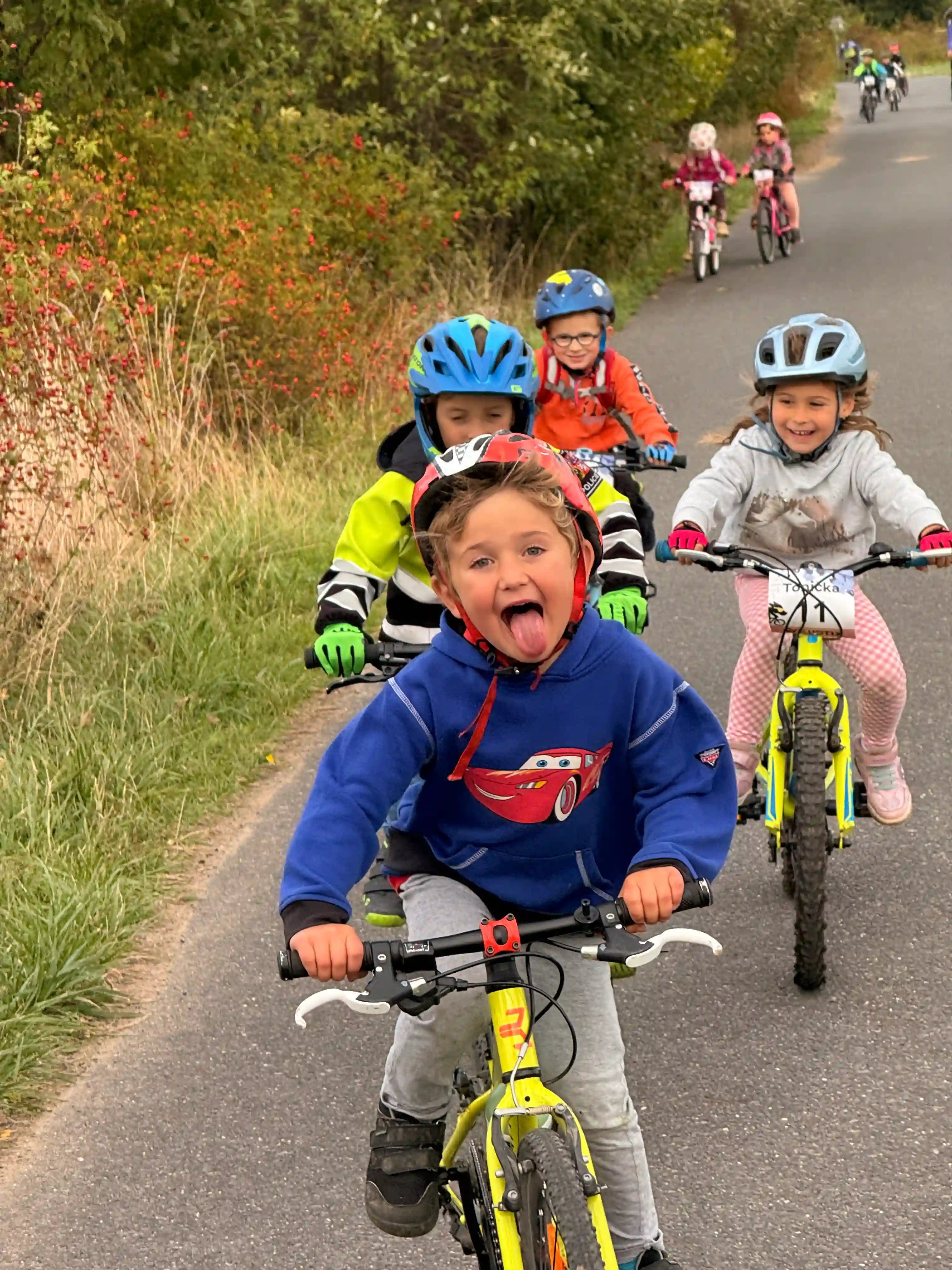 Děti jedou za sebou na kole a smějí se přitom.