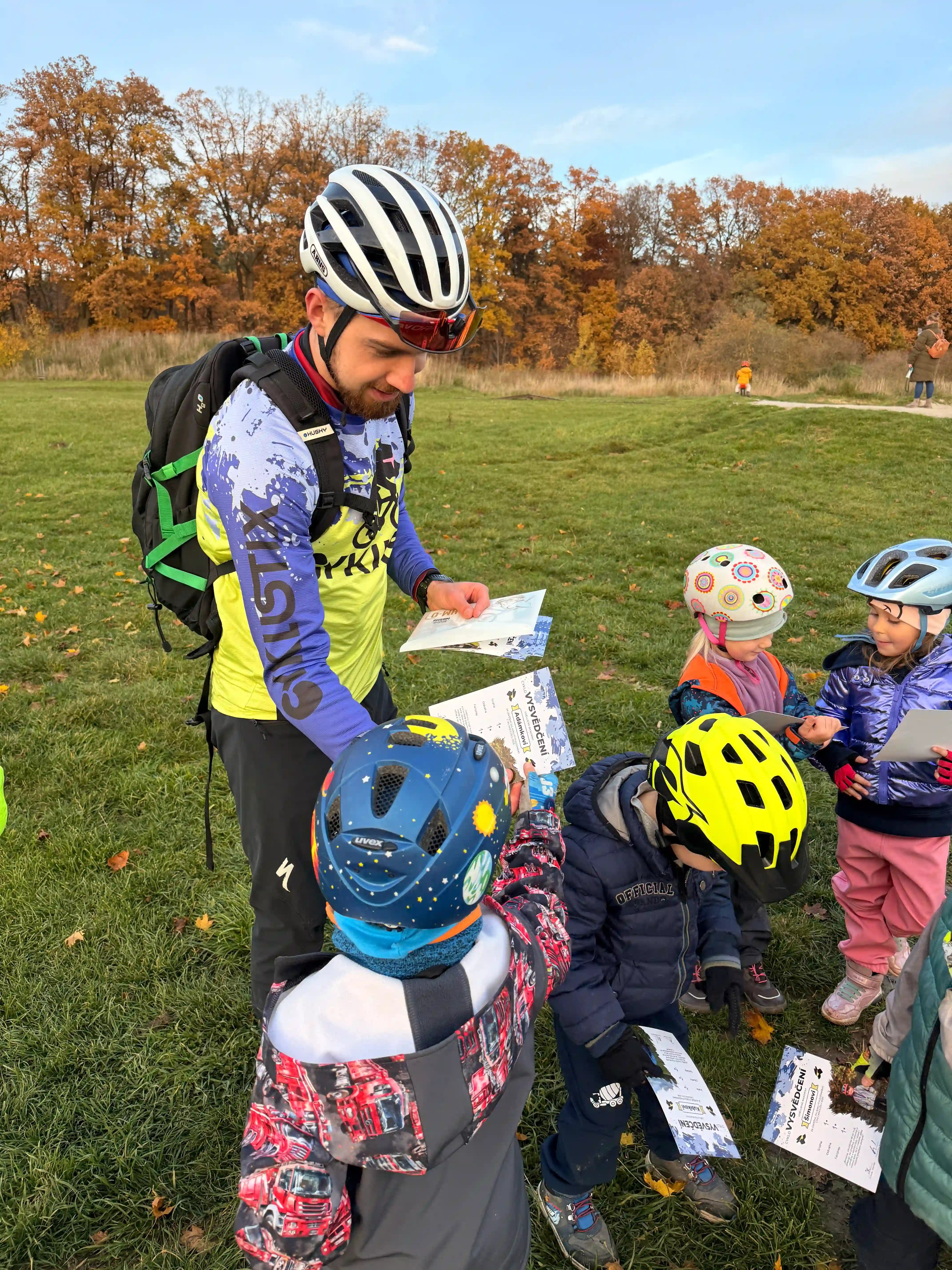 Trenér rozdává vysvědčení dětem z cyklokroužku.